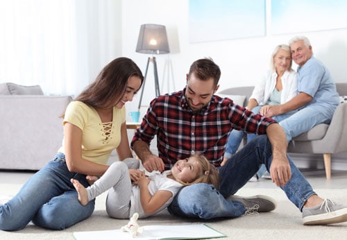 A family sitting on the floor in a cozy living room, enjoying each other's company.