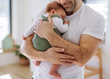 Father holding a newborn baby close, symbolizing paternity and fatherhood rights